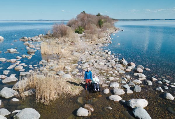 Bilden tagen uppifrån, visar ett stenigs parti ut till en halvö. På bilden ser man två personer. En av dem sitter i en Zoom Uphill, en terränggående elrullstol.